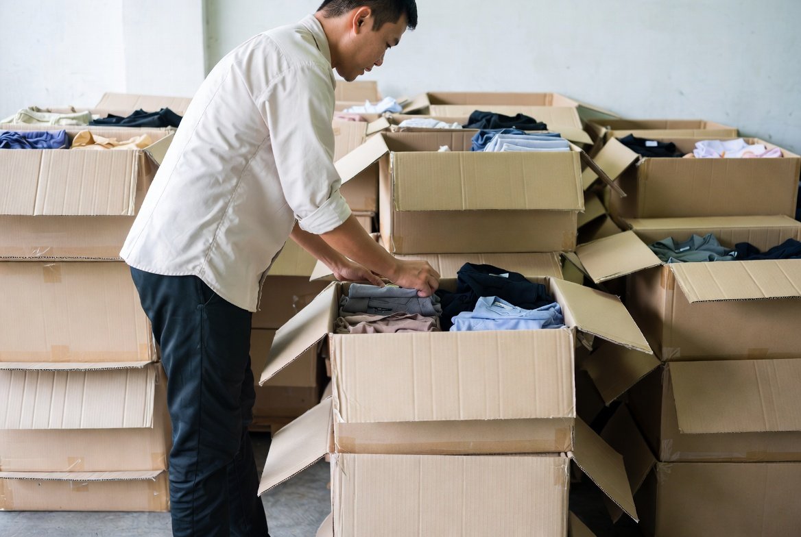 Cartons of plain, unbranded folded clothing being checked and packed for a wholesale order
